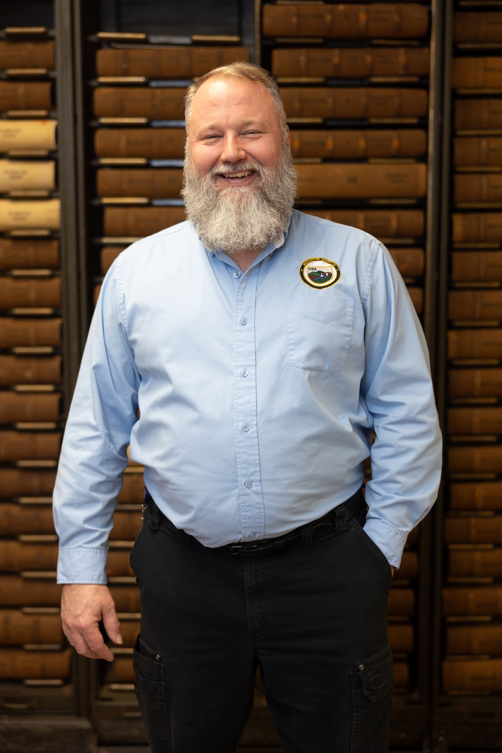 man smiles for photo in front of books