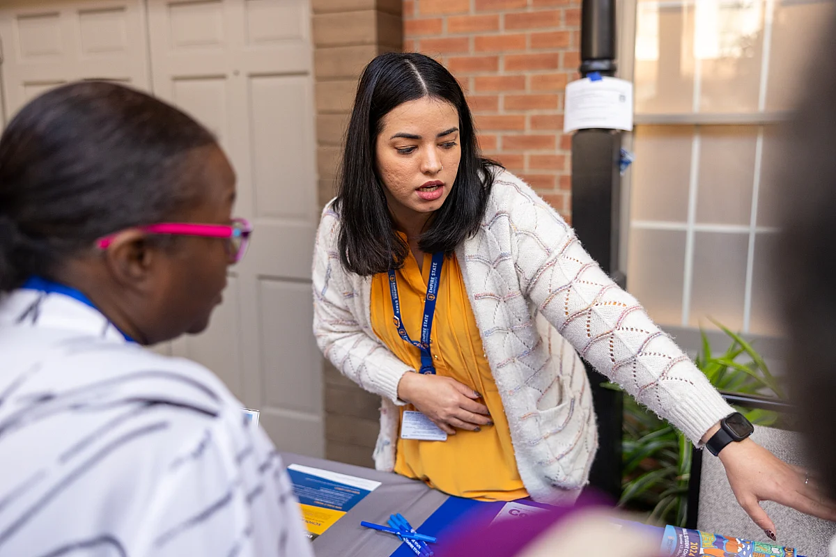 Two women have a discussion at an event table.