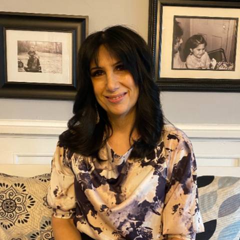 a woman sits in front of wall with picture frames