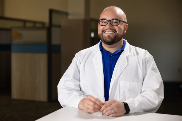 student in labcoat smiles for photo