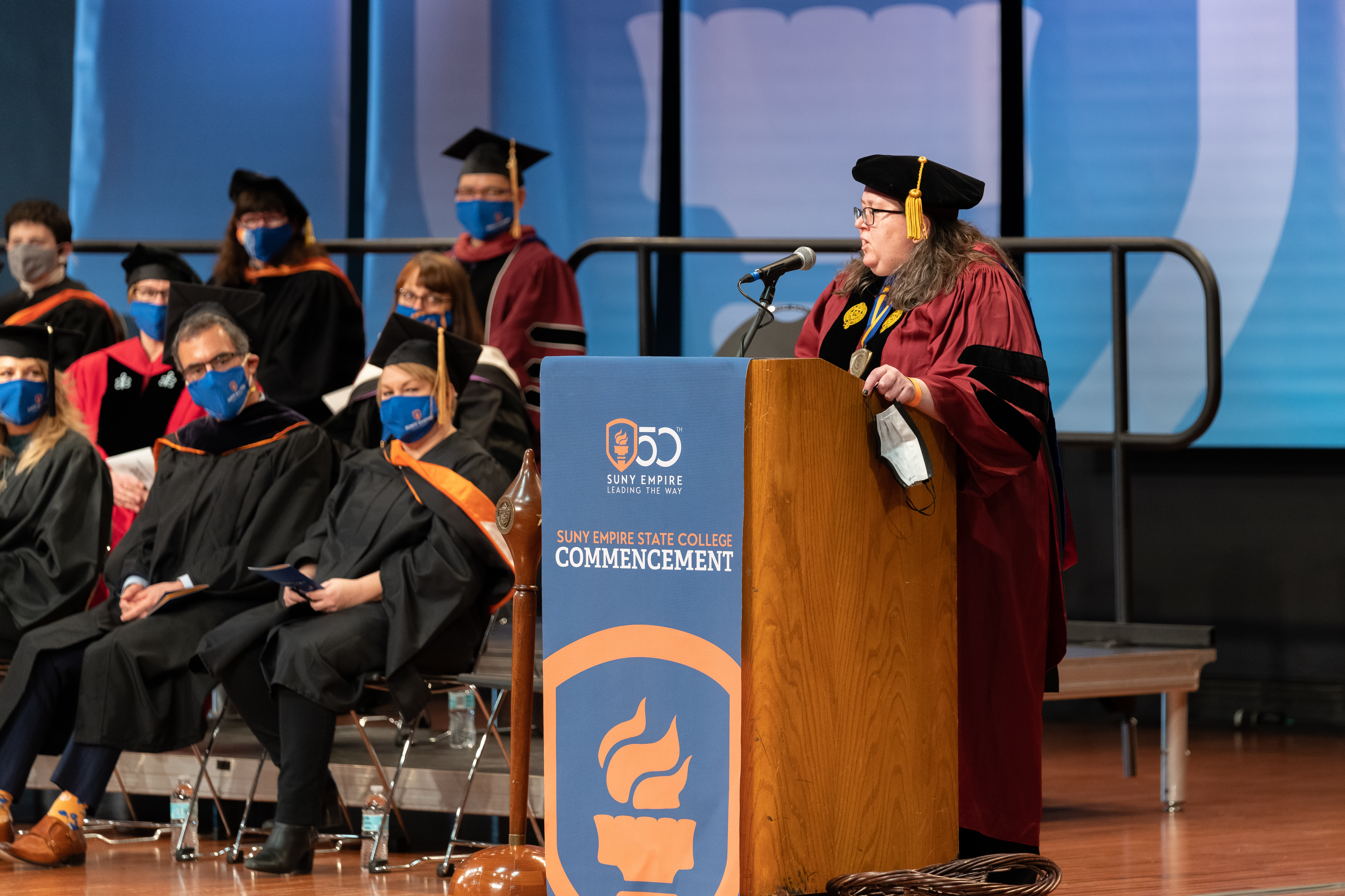 Thalia MacMillan speaks at a podium during a commencement ceremony.