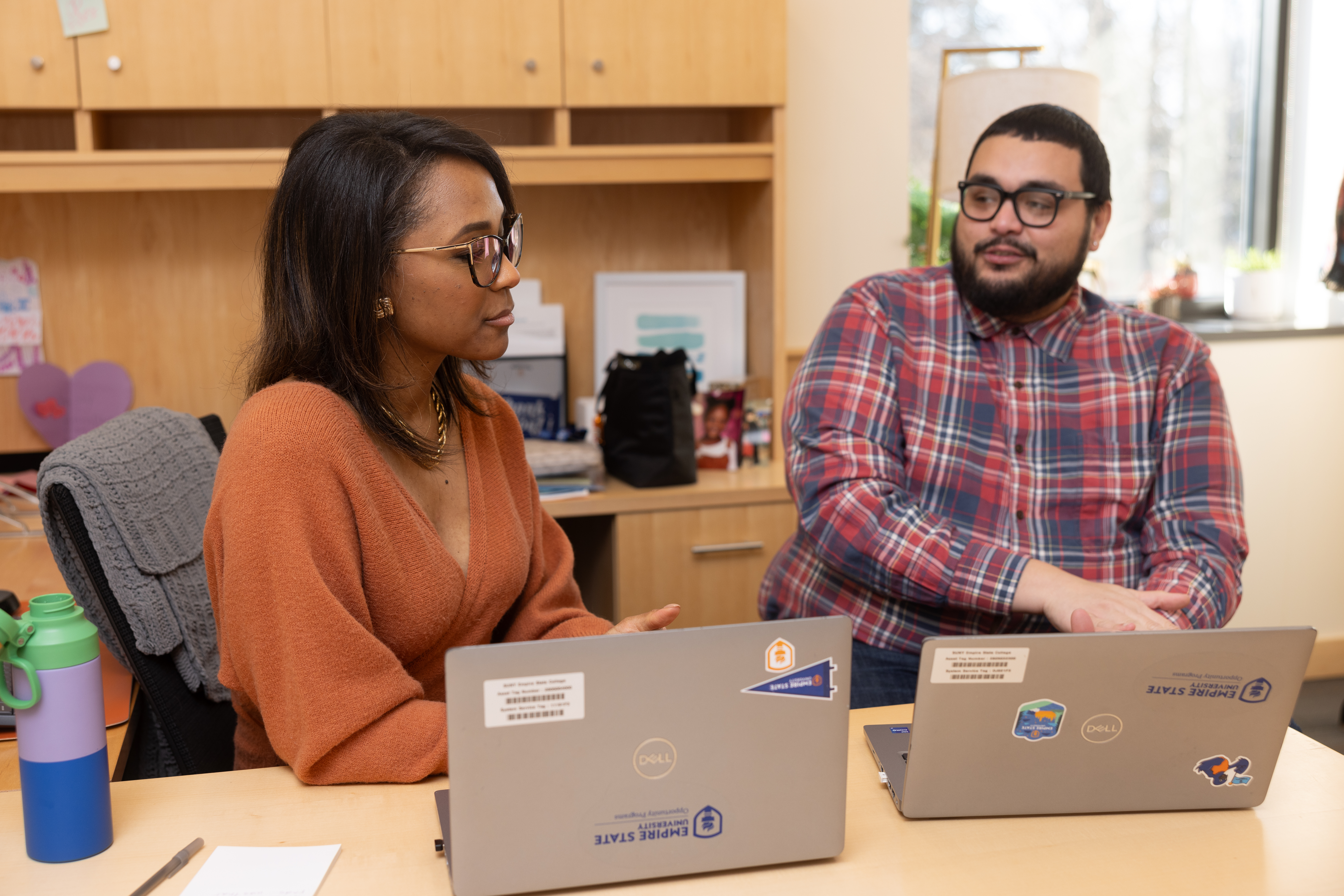 Man consults with a woman at a desk.