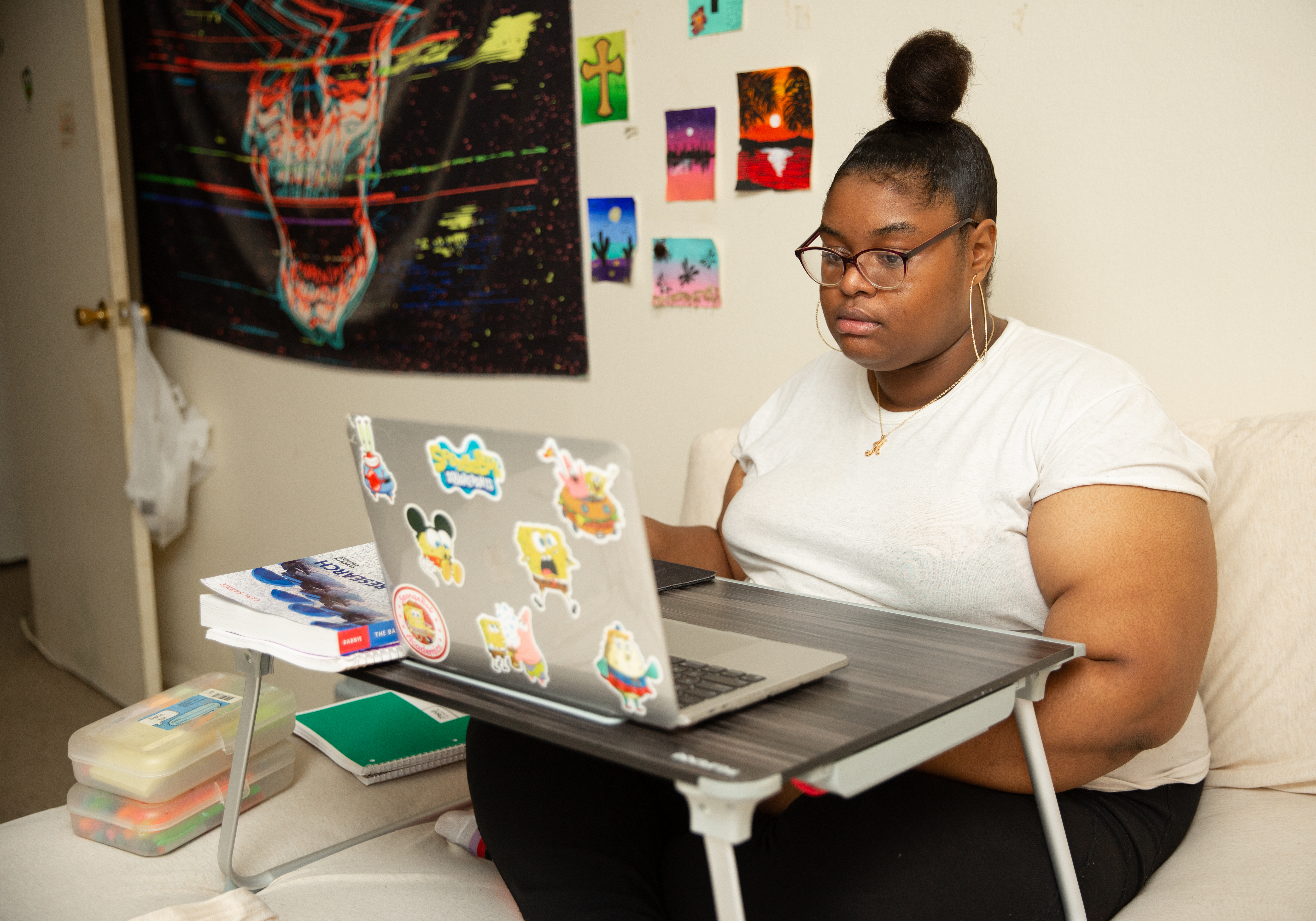 A woman sits on a bed using a laptop.